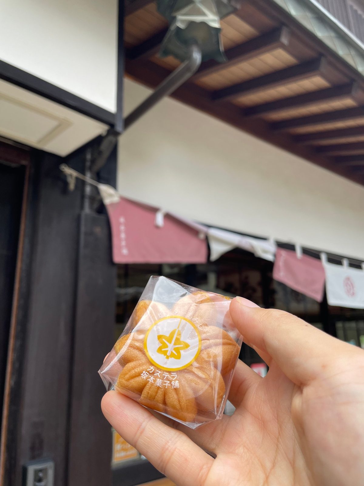 A maple-leaf-shaped momiji manju cake held in front of a shop