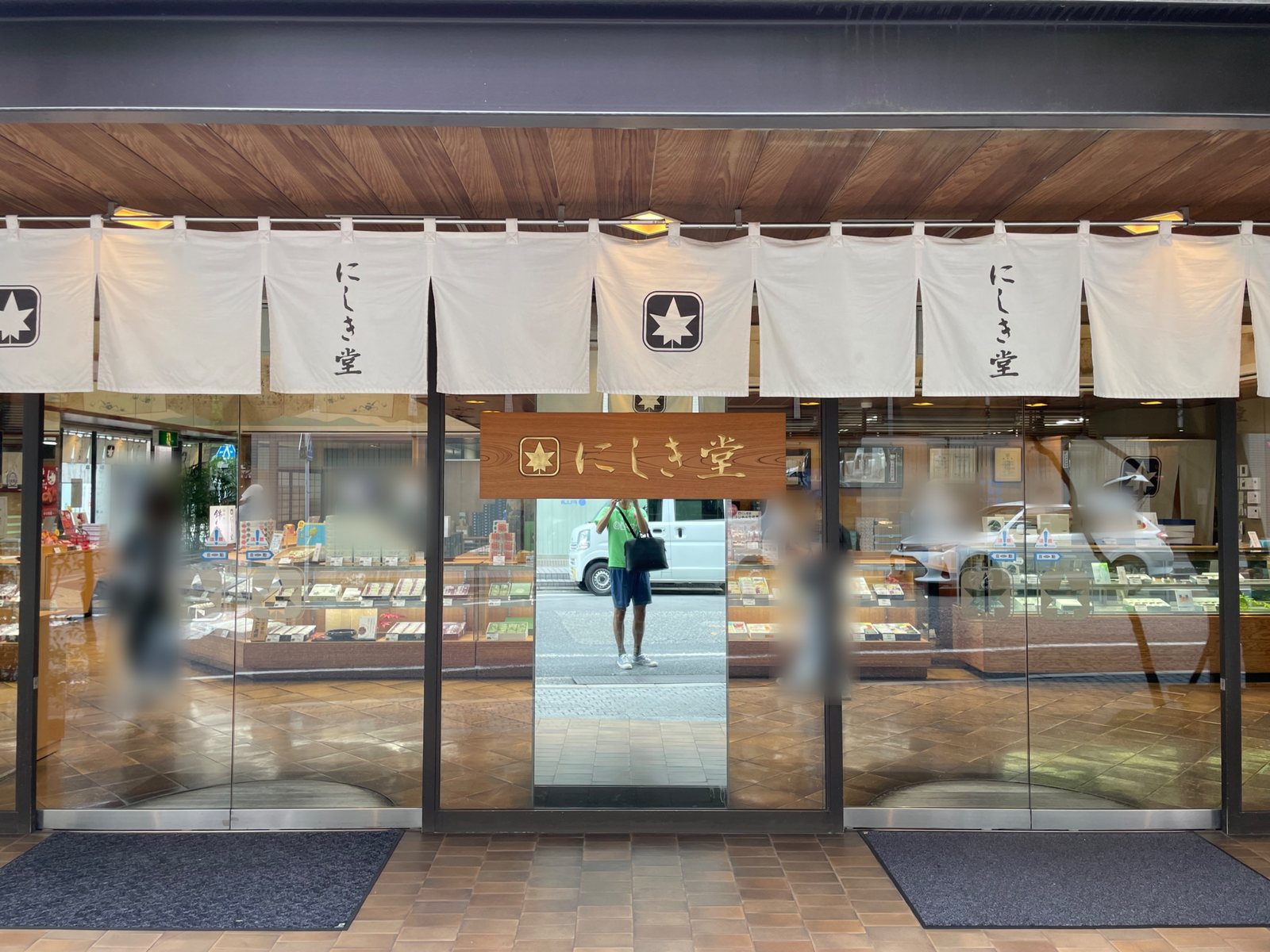 The front of Nishikido main store with white noren curtains and a wooden sign